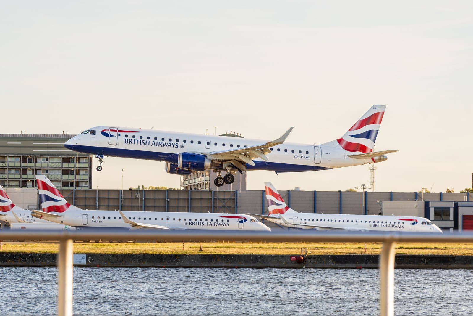 British Airways aircraft above the runway with other British Airways aircraft behind it