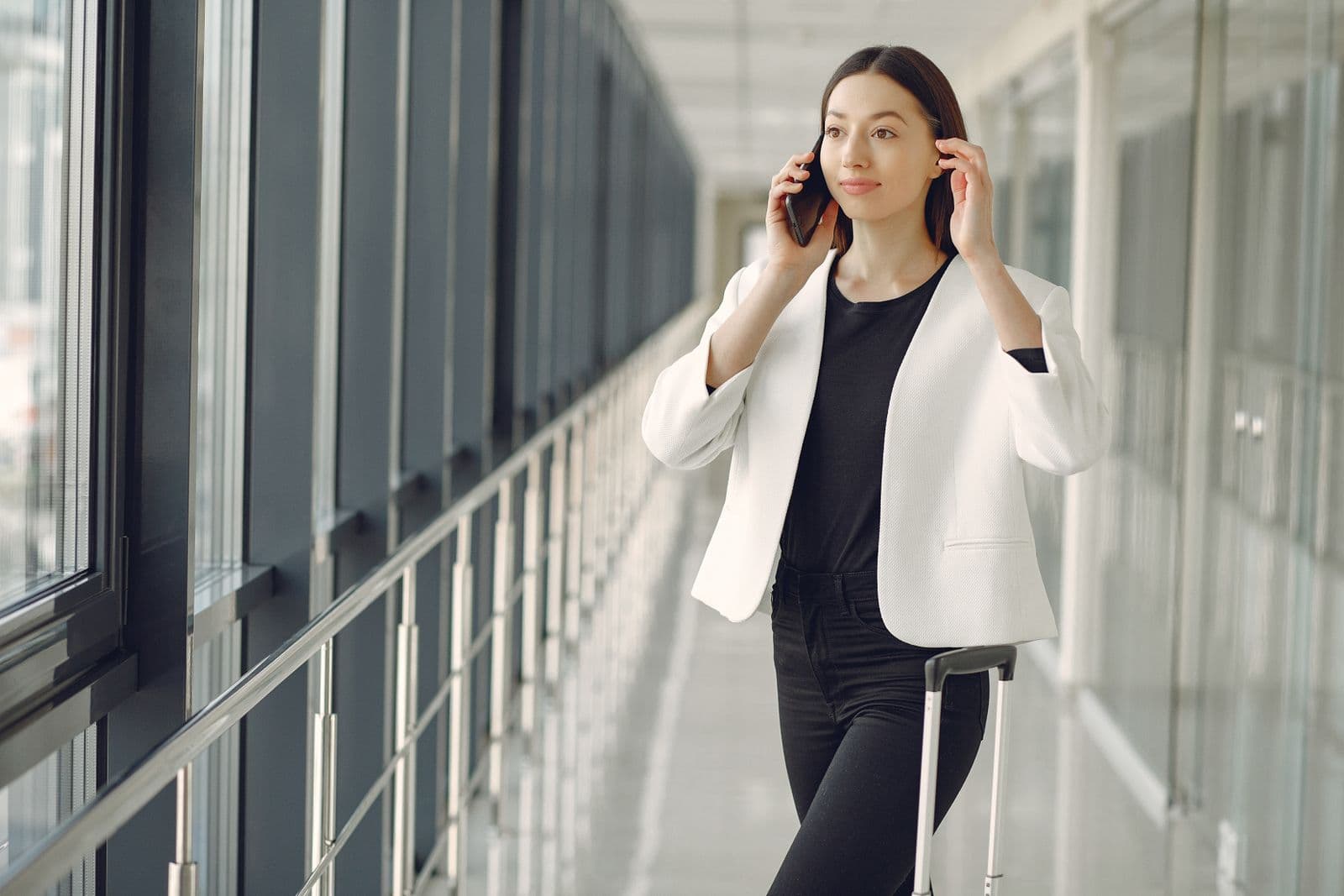 Traveler with a suitcase making a phone call in an airport corridor
