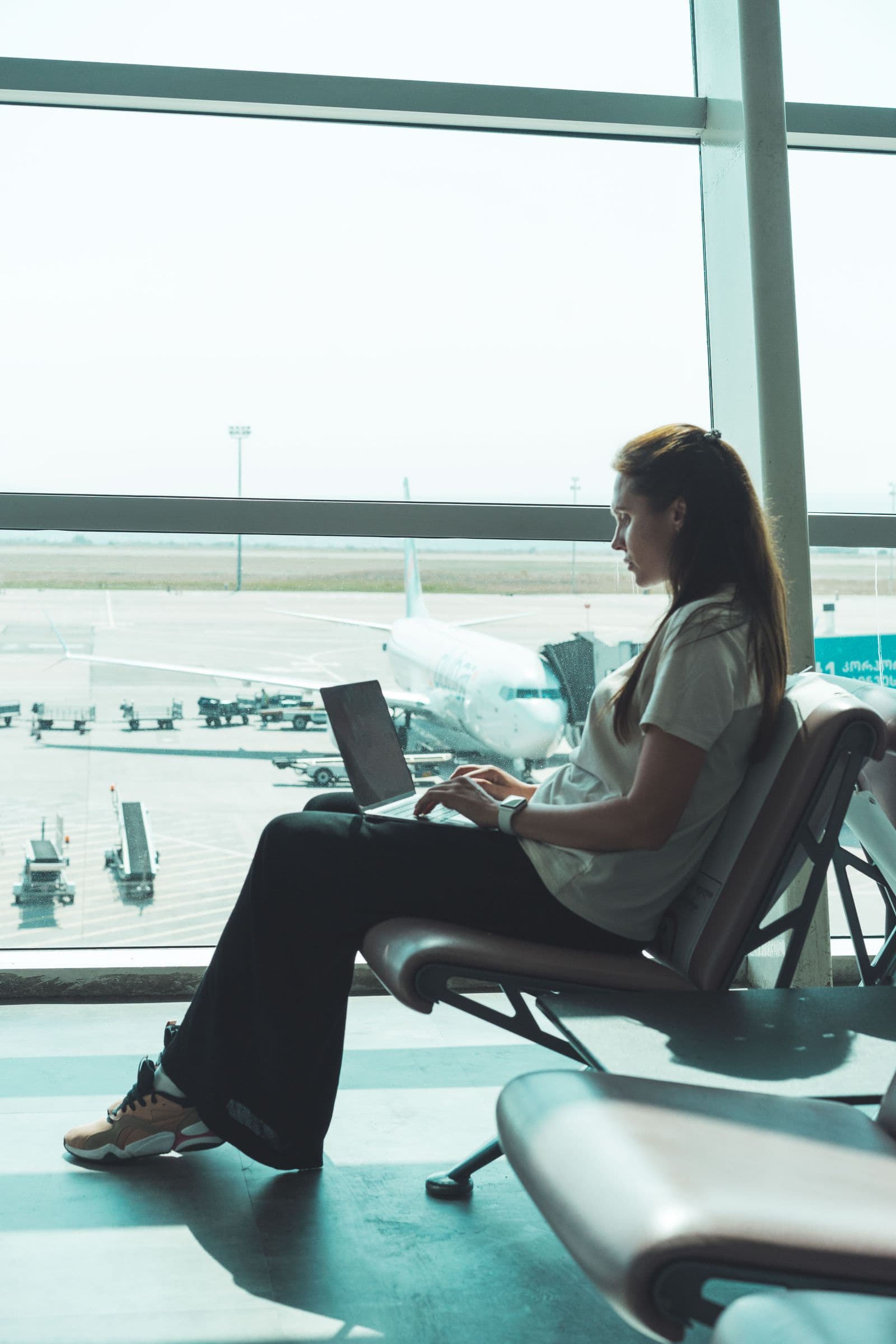 Traveler researching flights on a laptop beside the airport gates