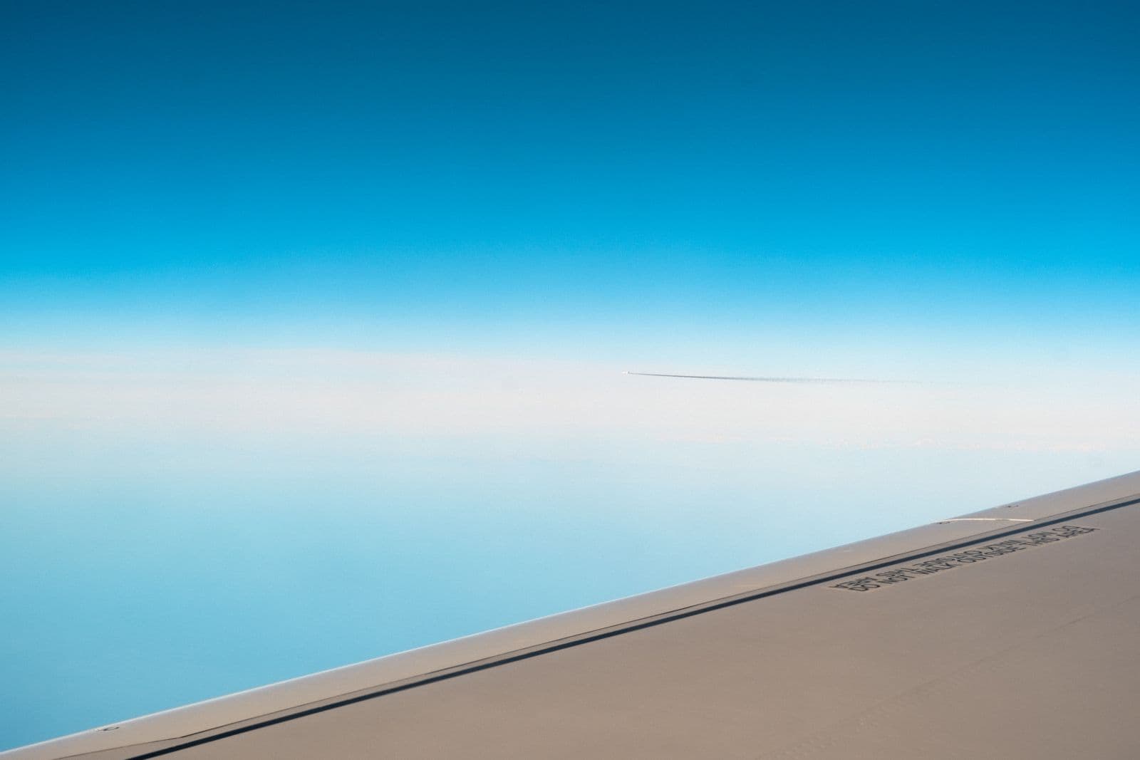 Unbranded airplane wing above a clear blue sky
