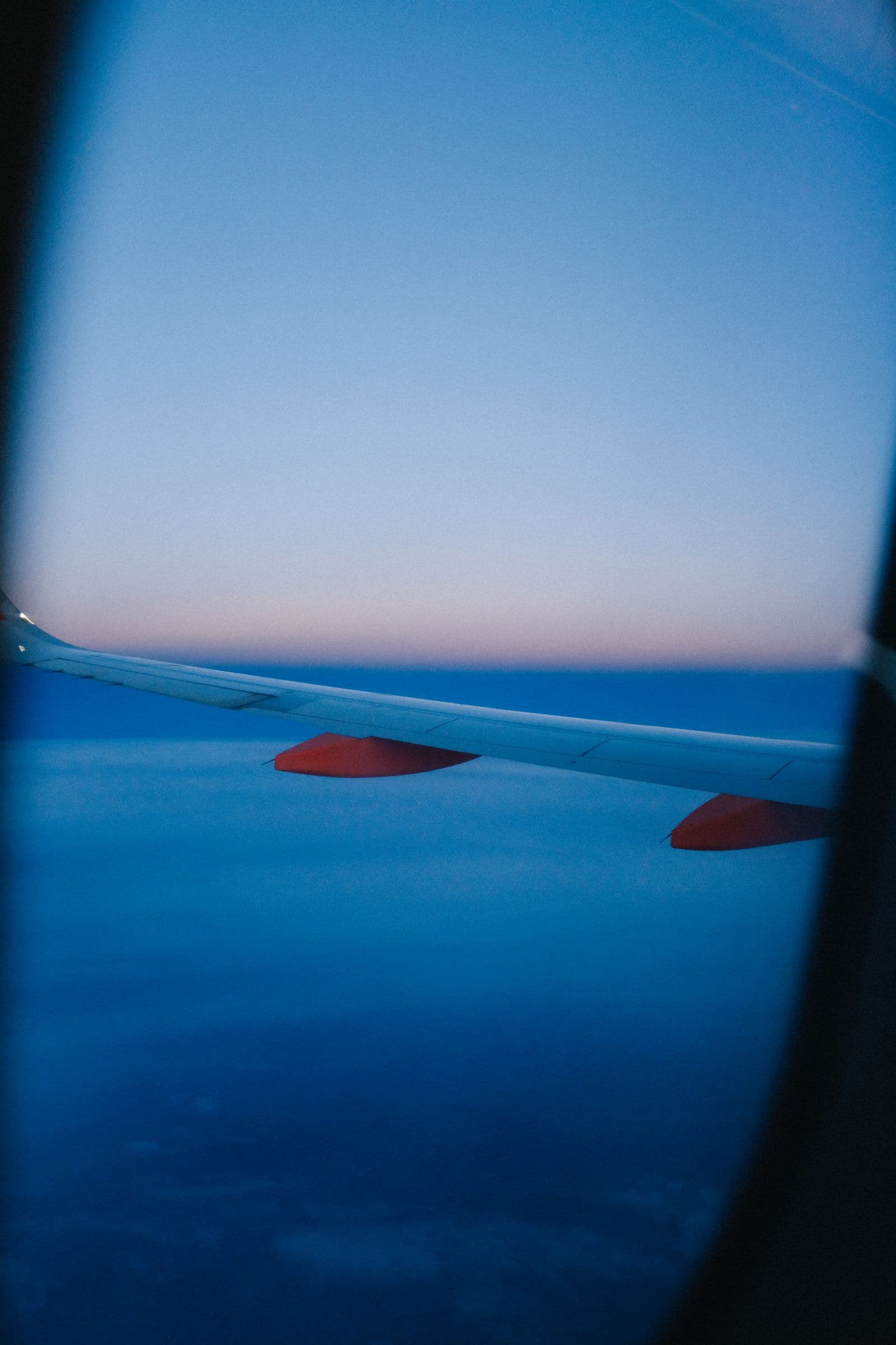 Unbranded airplane wing viewed through a passenger window