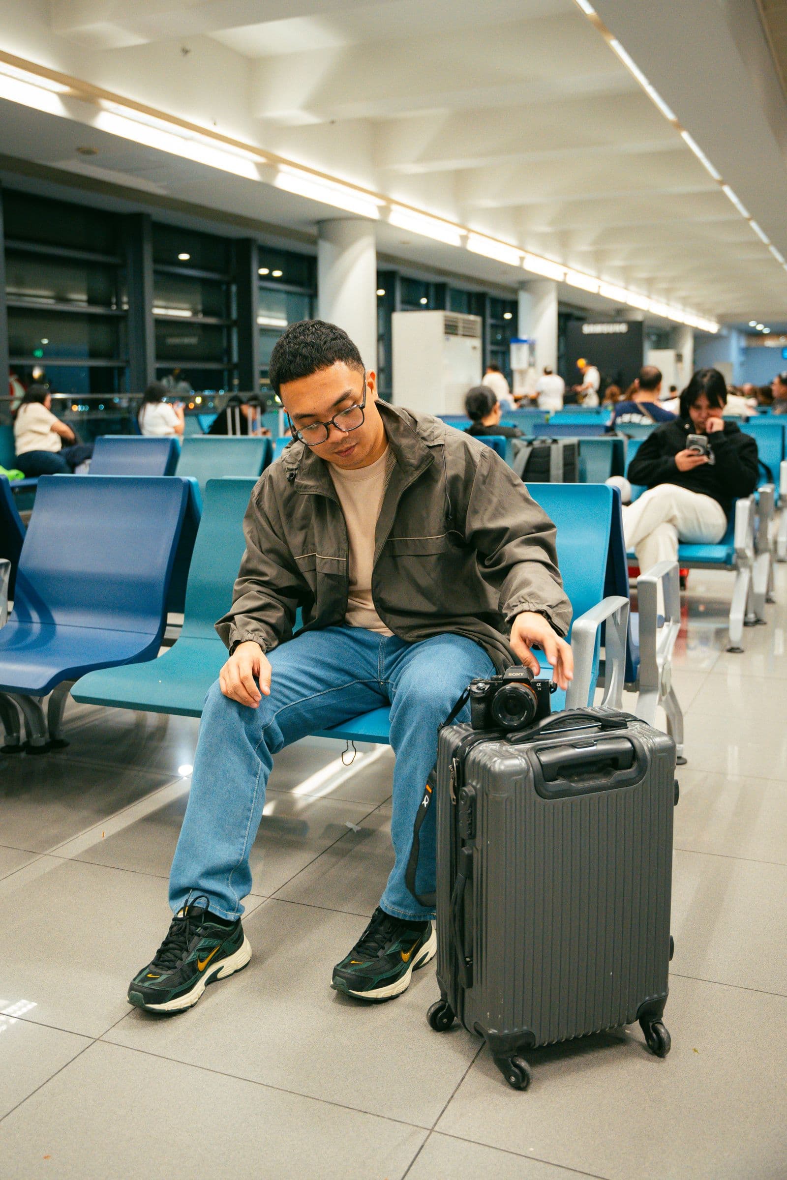Traveler seated with luggage inside a modern airport terminal
