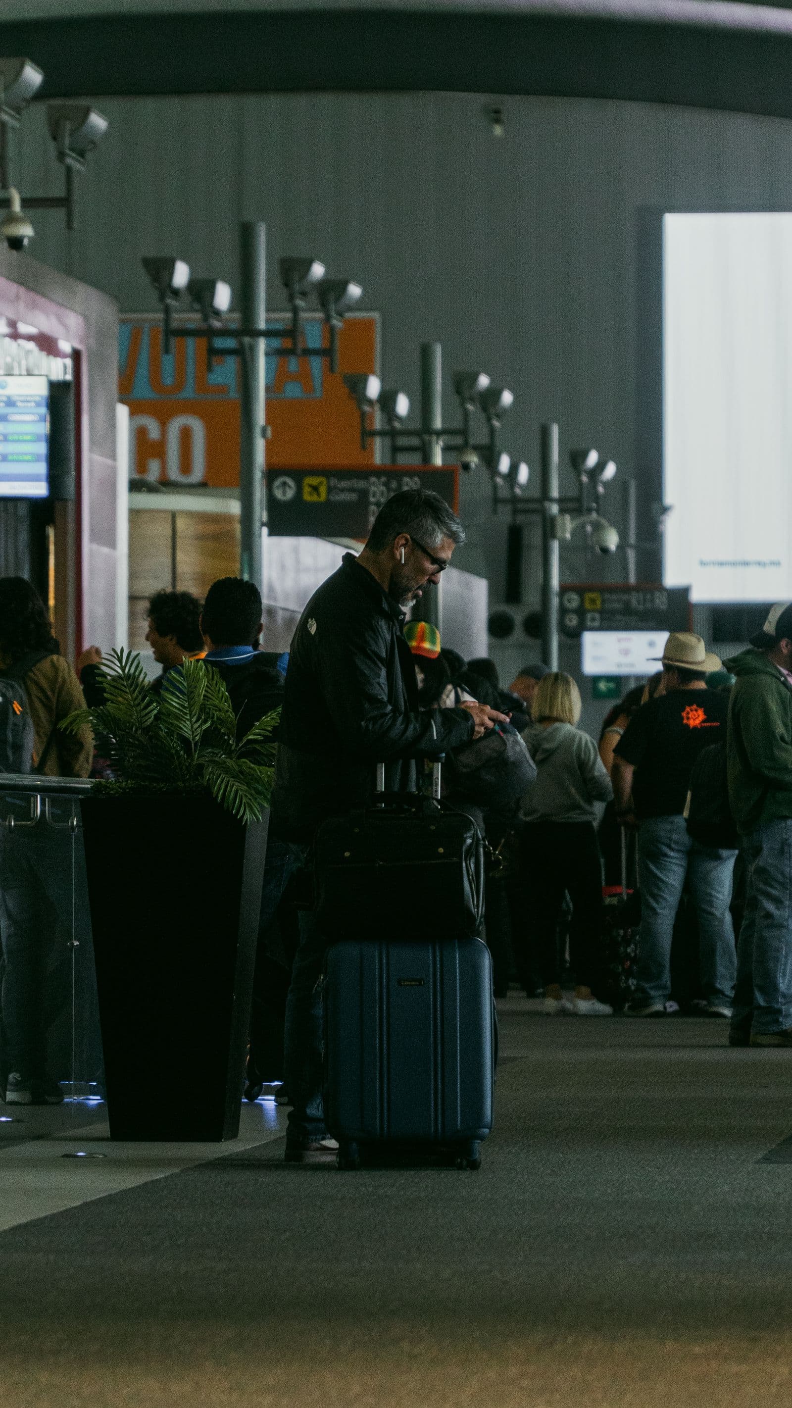 Traveler checking a phone beside luggage at an airport gate