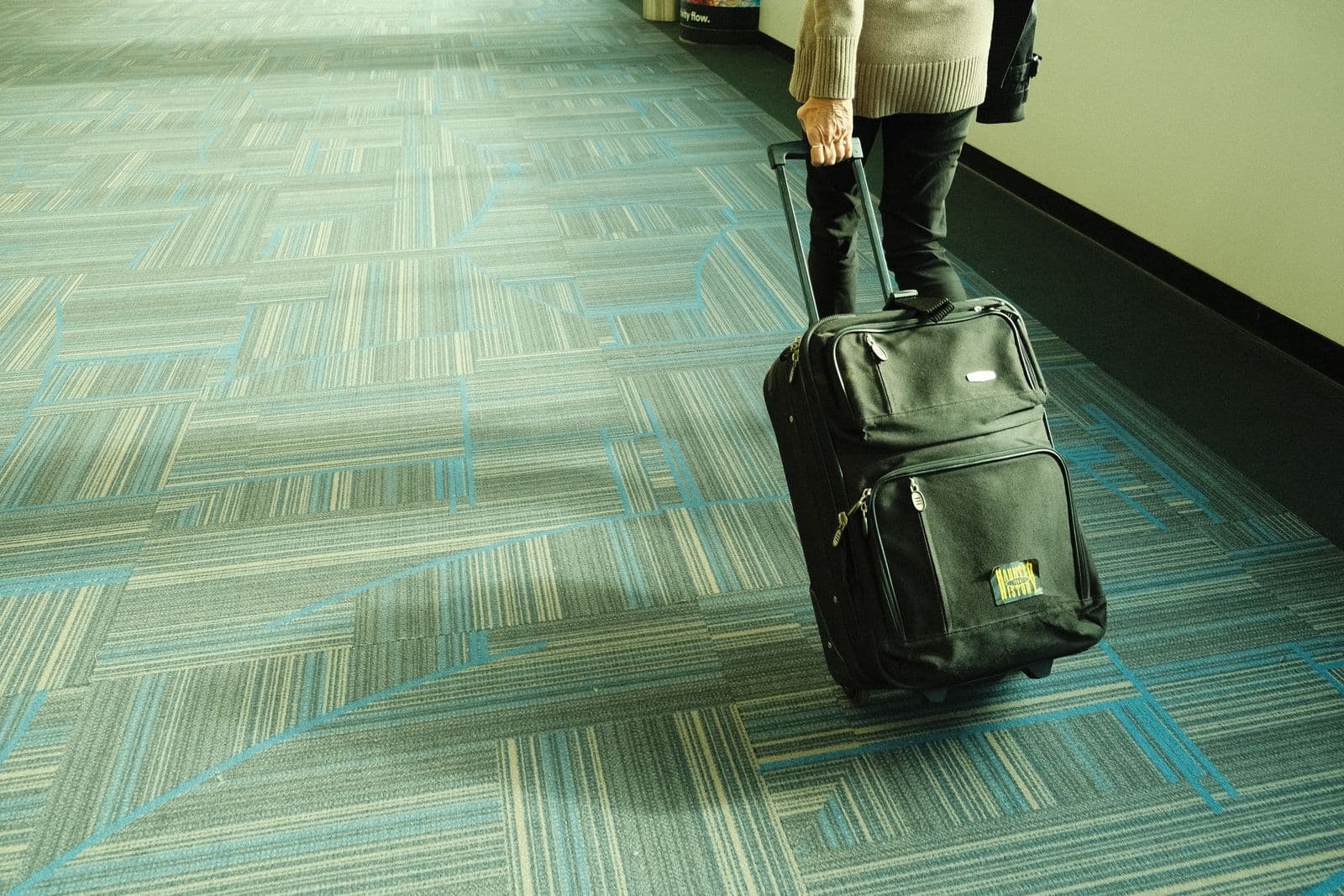 Traveler rolling luggage along an airport corridor