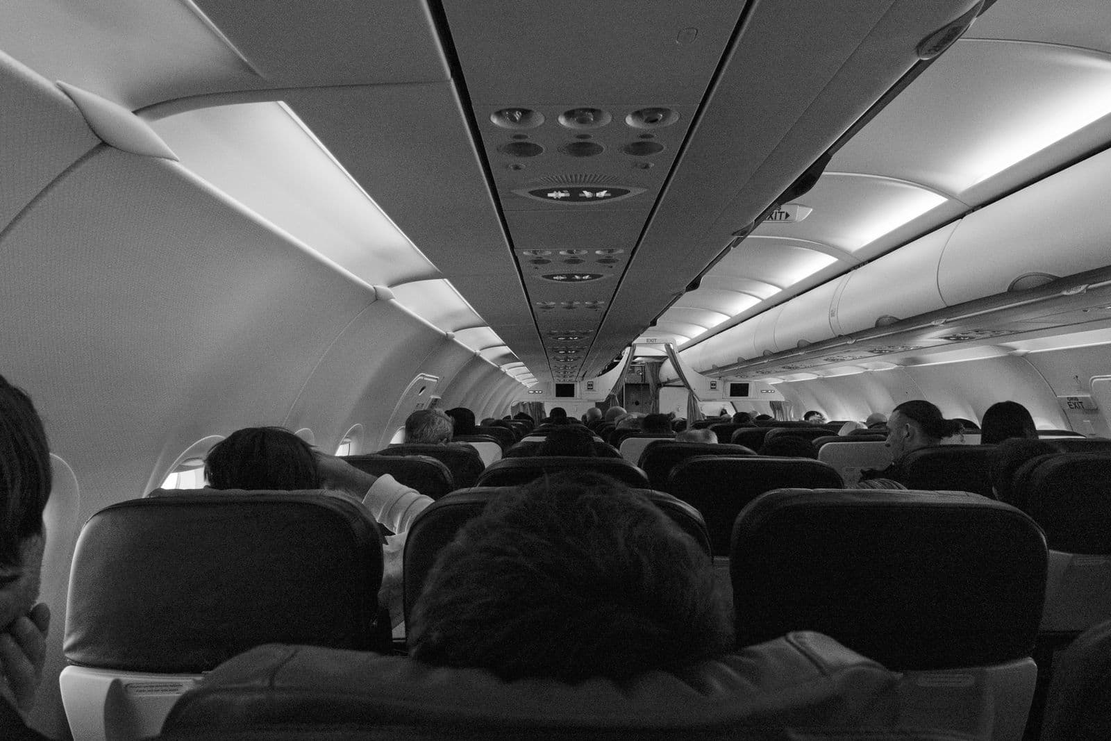 Monochrome view of passengers seated inside an airplane cabin