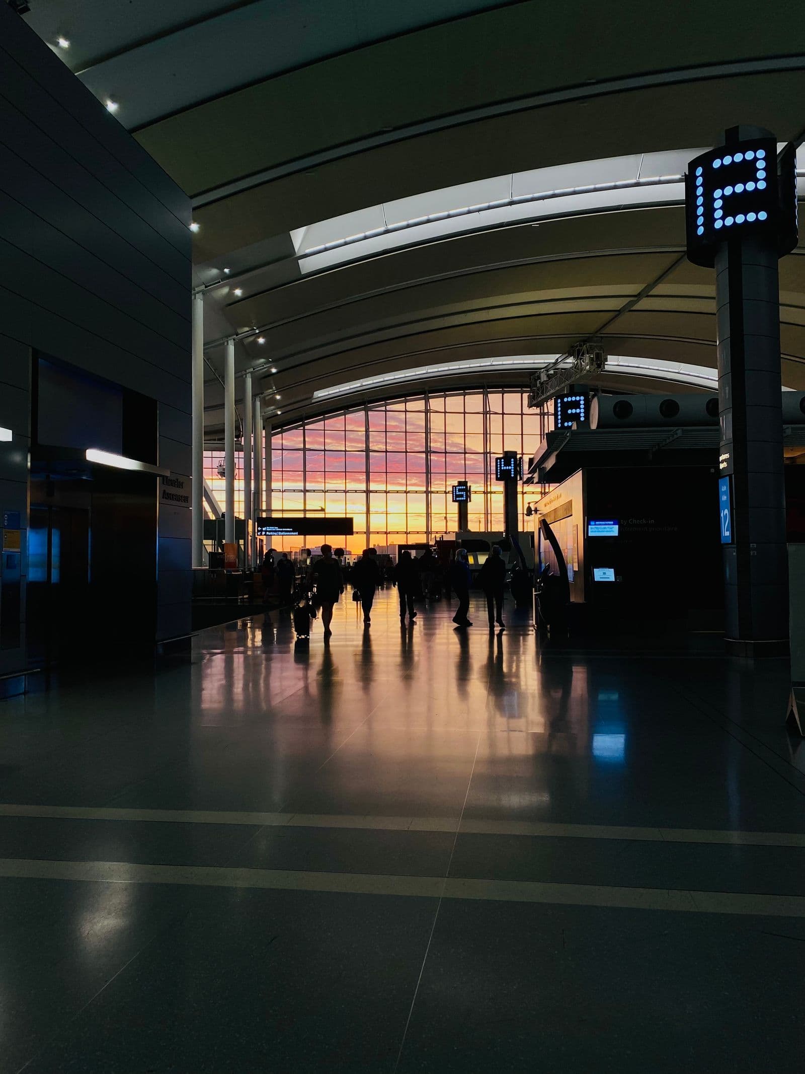 Travelers walking through a sunset-lit airport terminal
