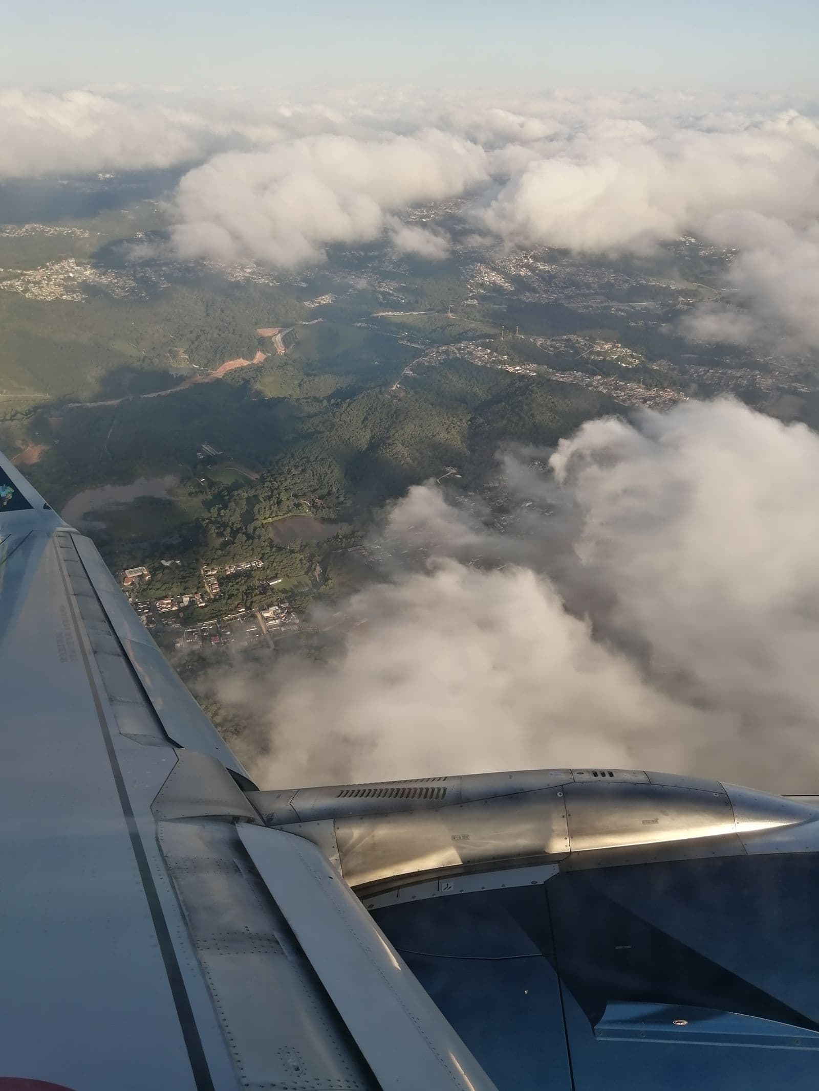 Airplane wing above a broad cloud-covered landscape