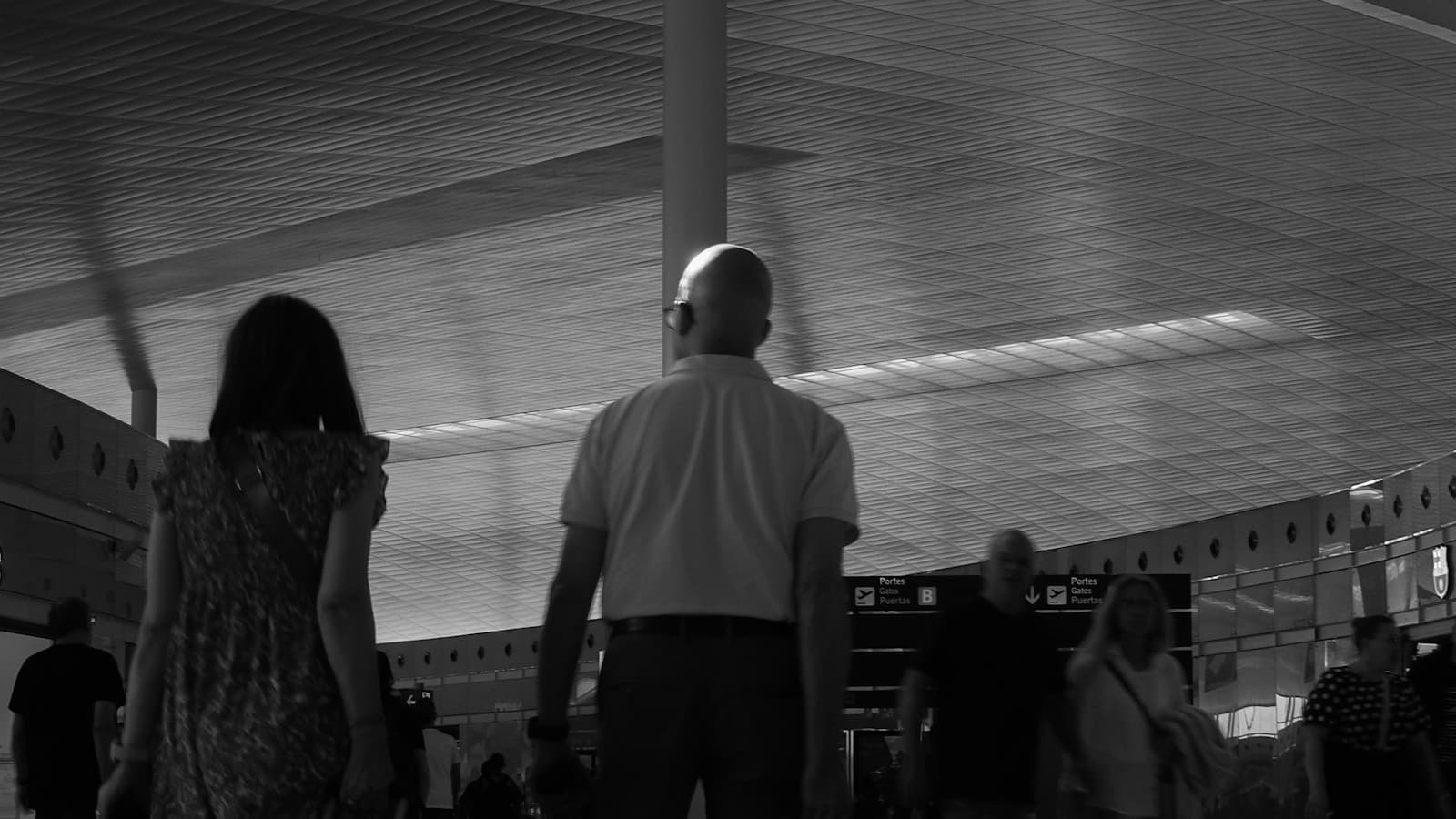 Two travelers walking together with luggage through a modern airport terminal