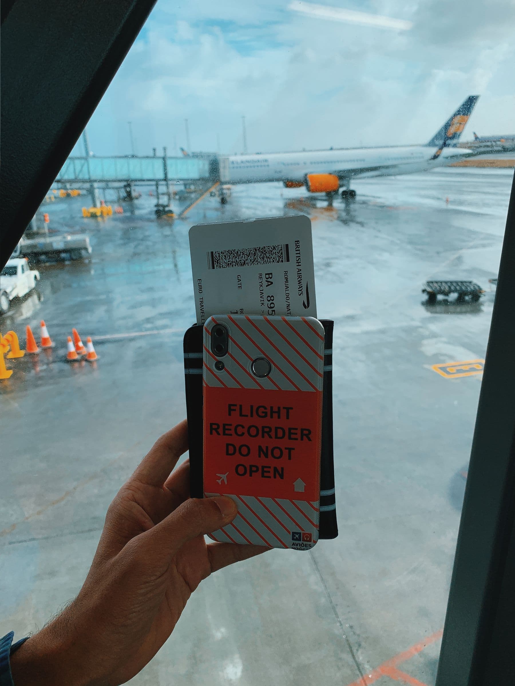 Traveler holding a boarding pass at an airport window with an aircraft outside