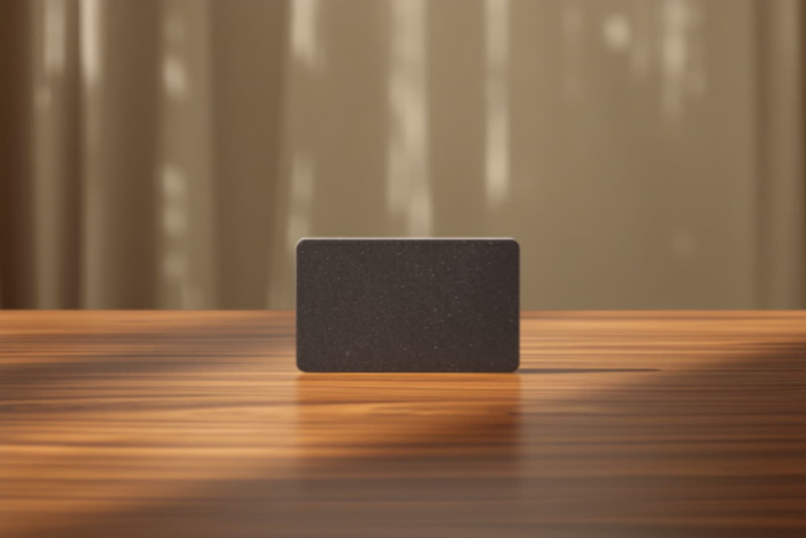 Dark hotel key card standing on a polished wooden reception desk in warm daylight