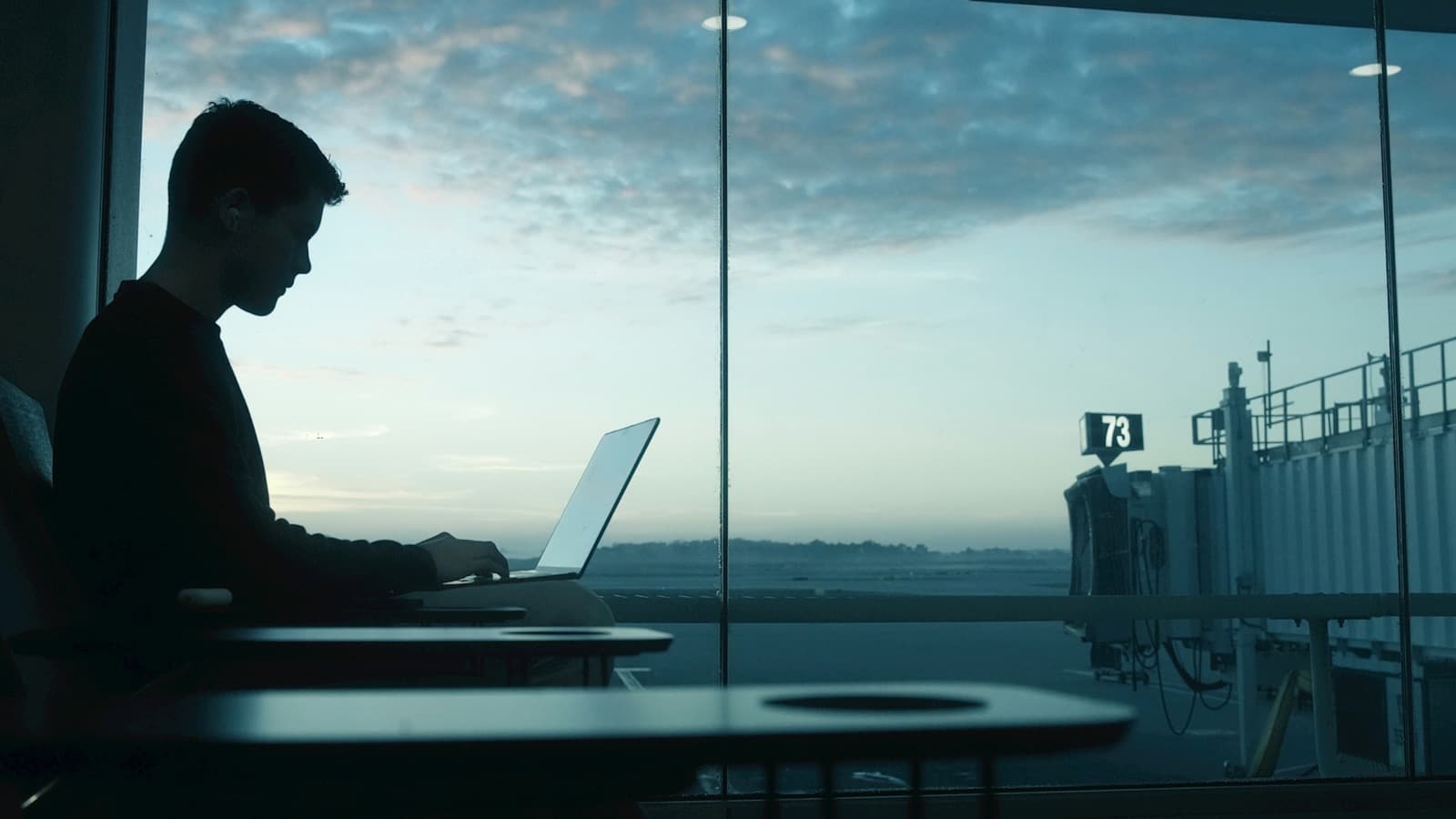 Traveler searching for award flights on a laptop beside an airport gate