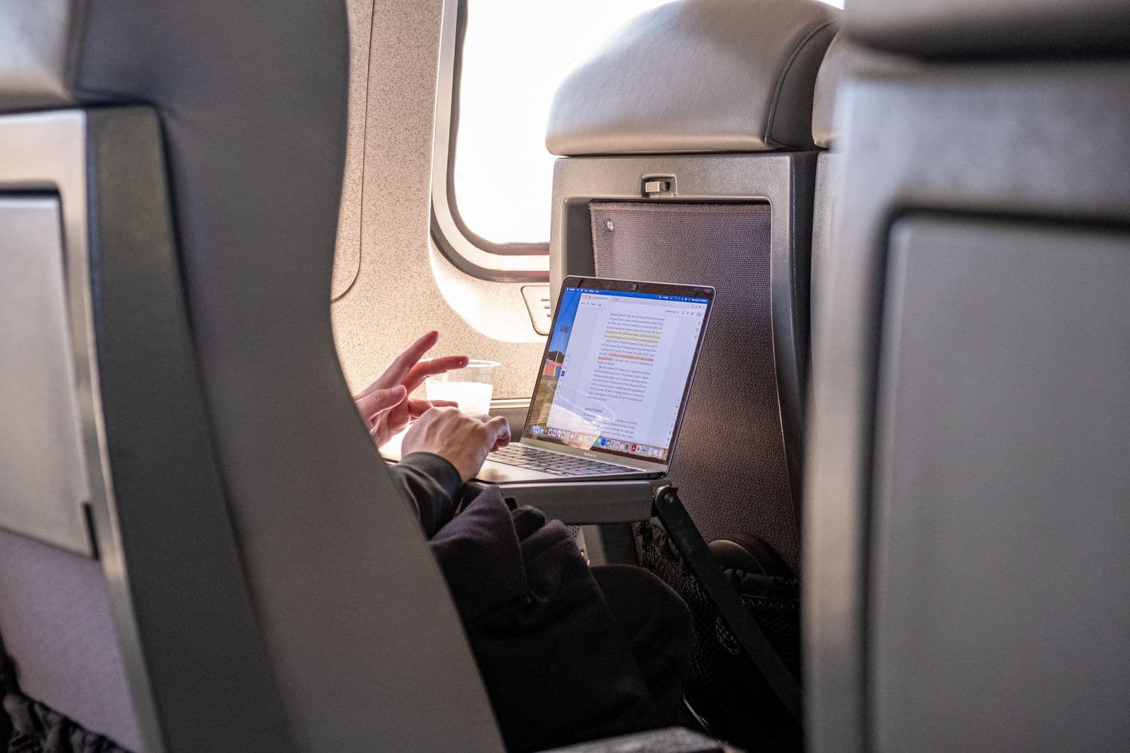 Traveler using a laptop from a premium airplane seat