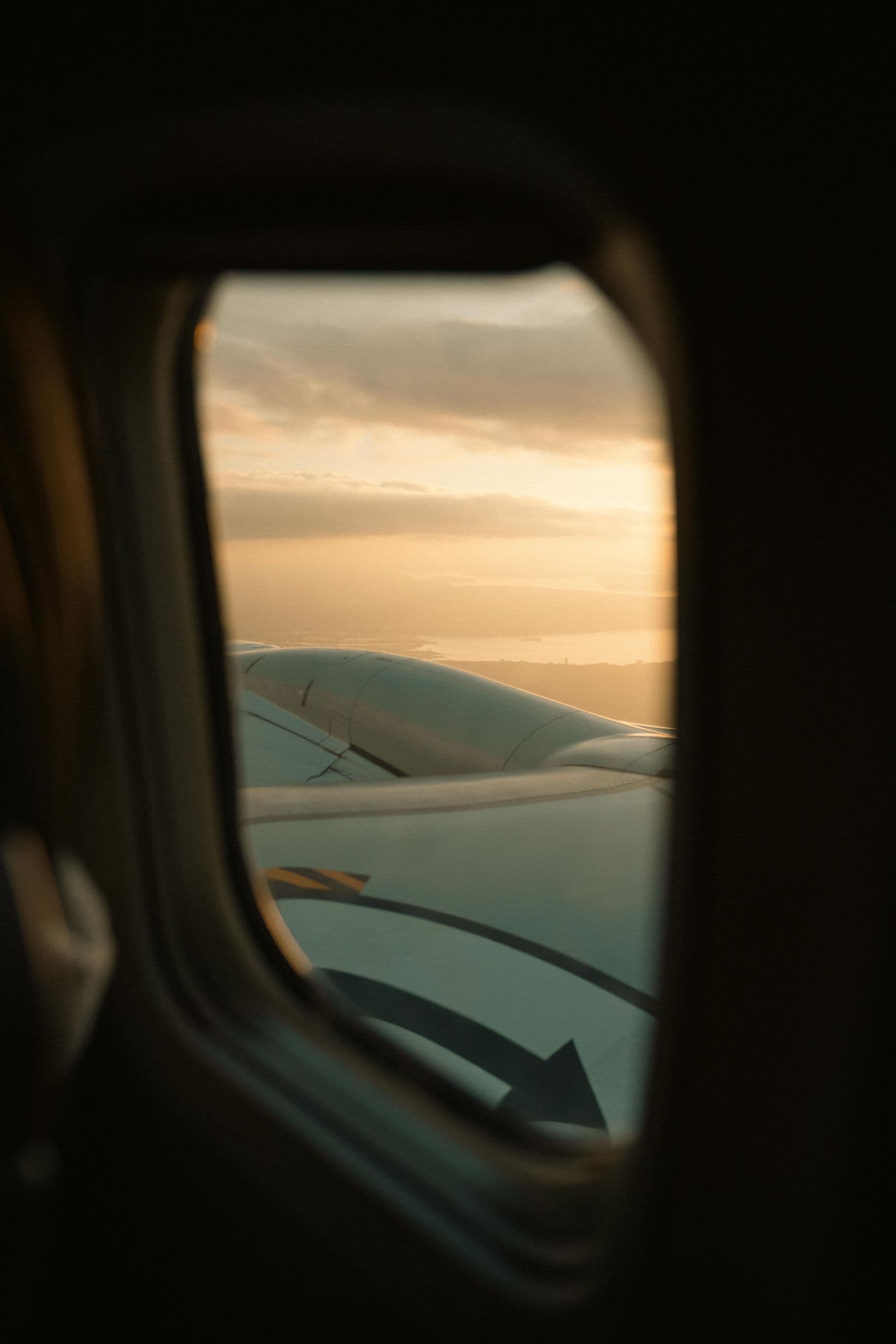 Airplane wing framed by a passenger window at sunset