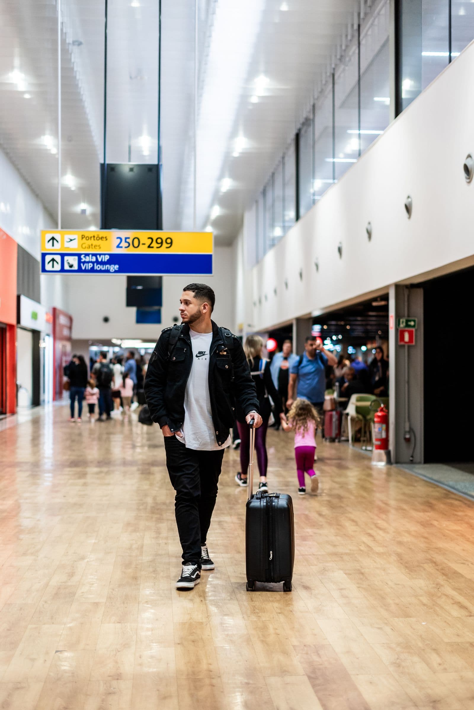 Traveler rolling luggage through a busy international airport