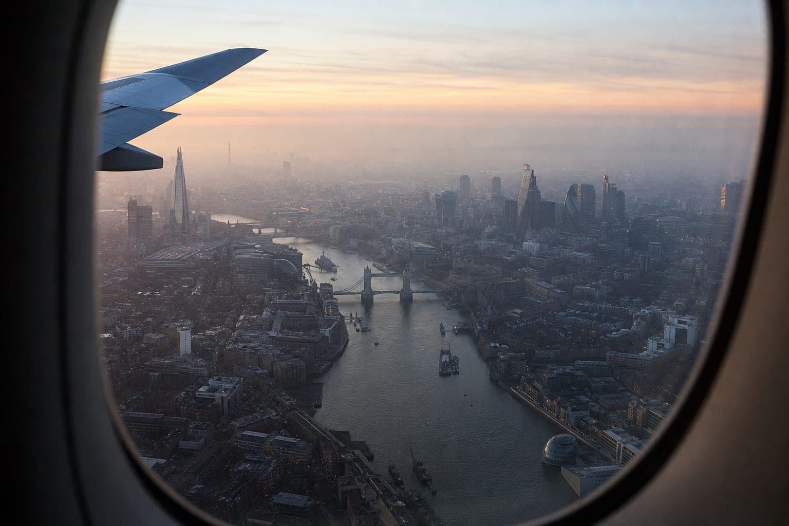 Airplane window view over the River Thames and London skyline at dawn
