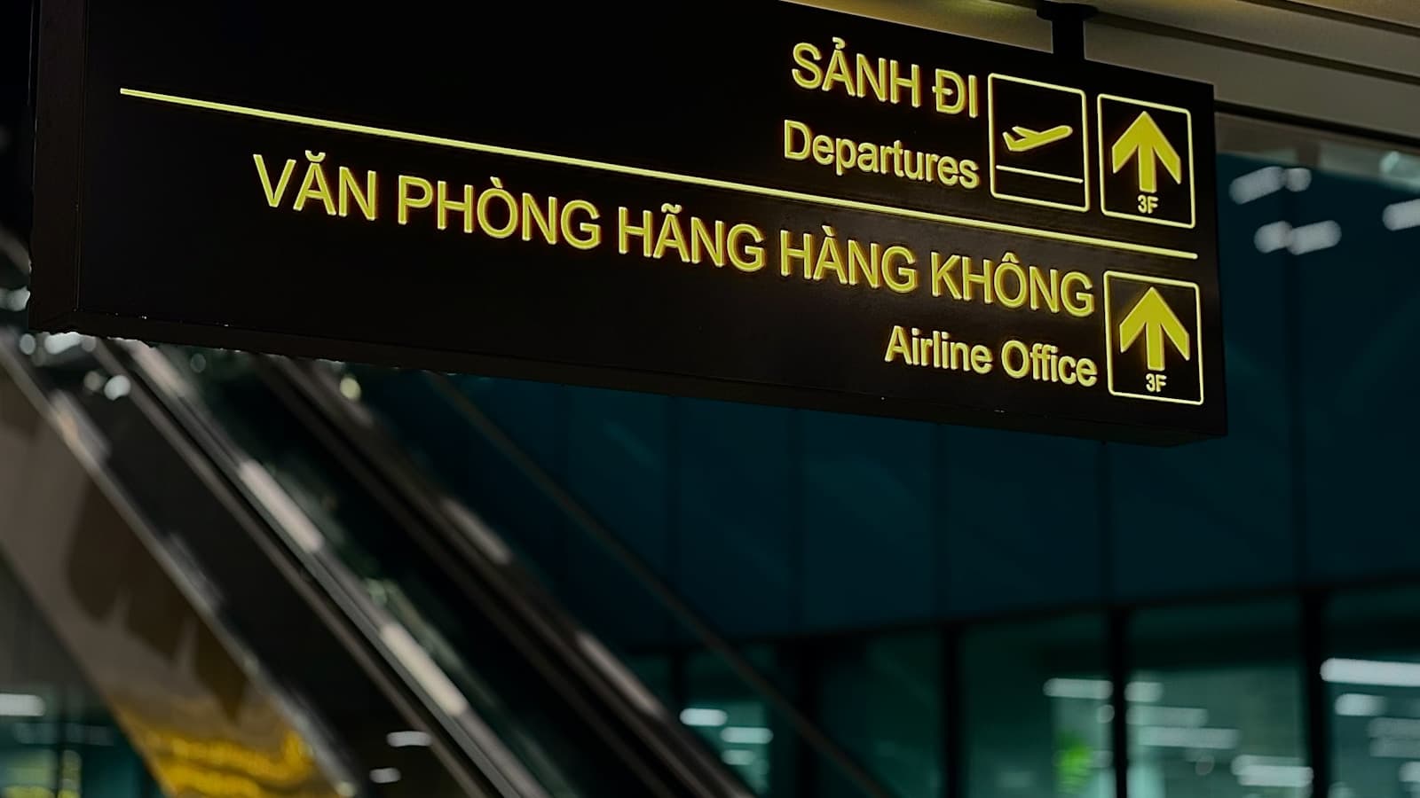 Airport departure and airline-office signs above an escalator