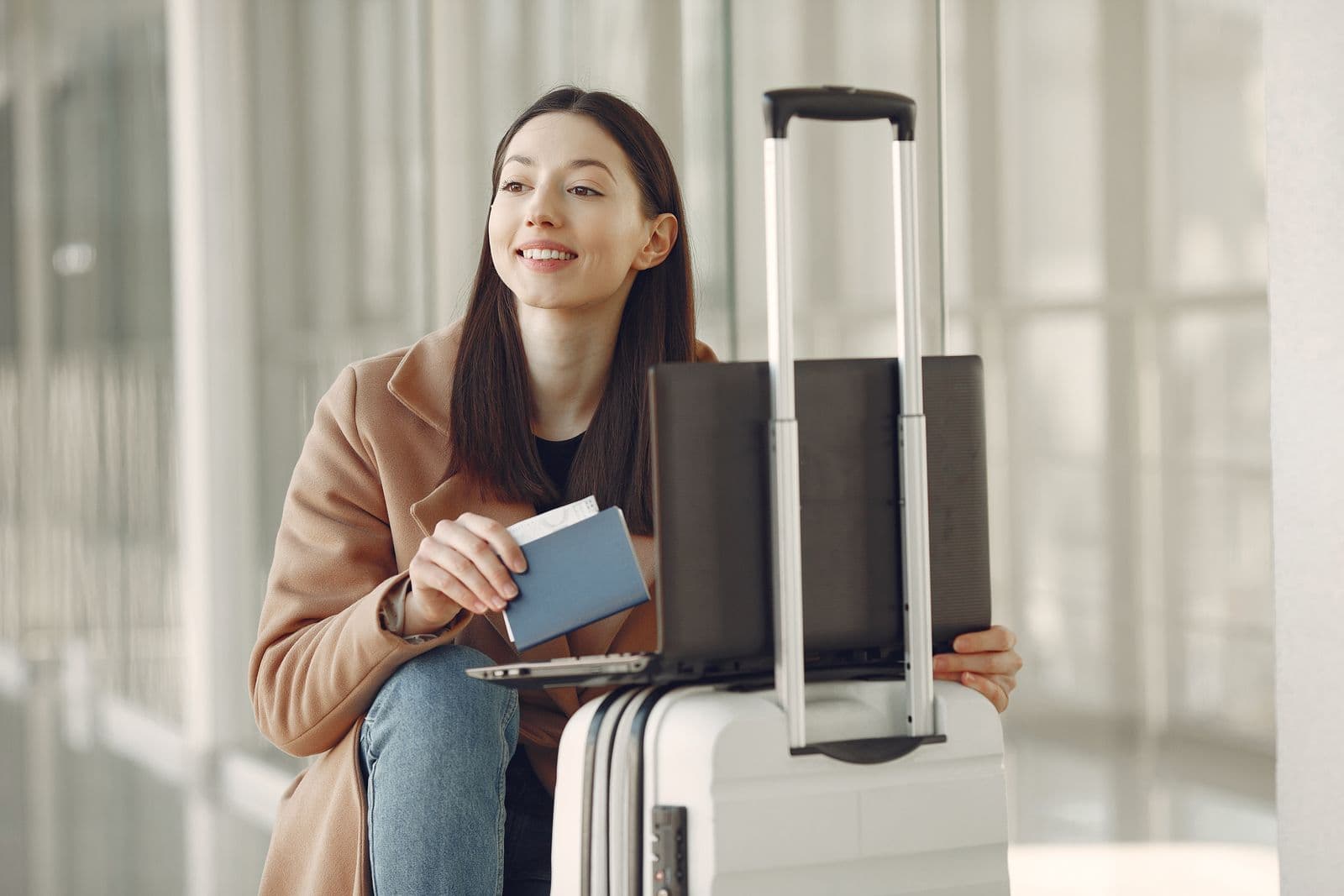 Traveler with a passport, laptop, and suitcase at an airport