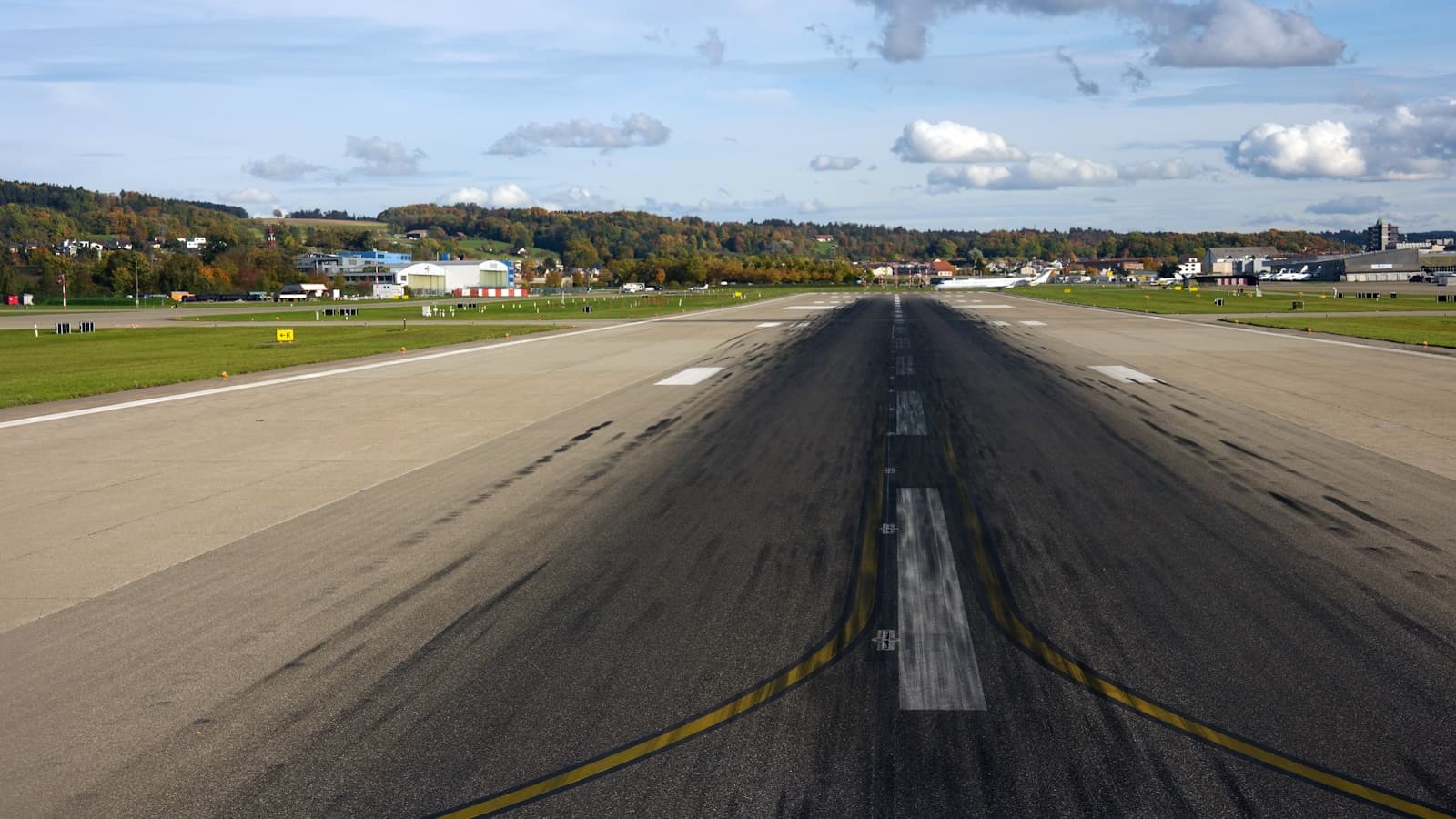 Empty airport runway stretching toward quiet terminal buildings