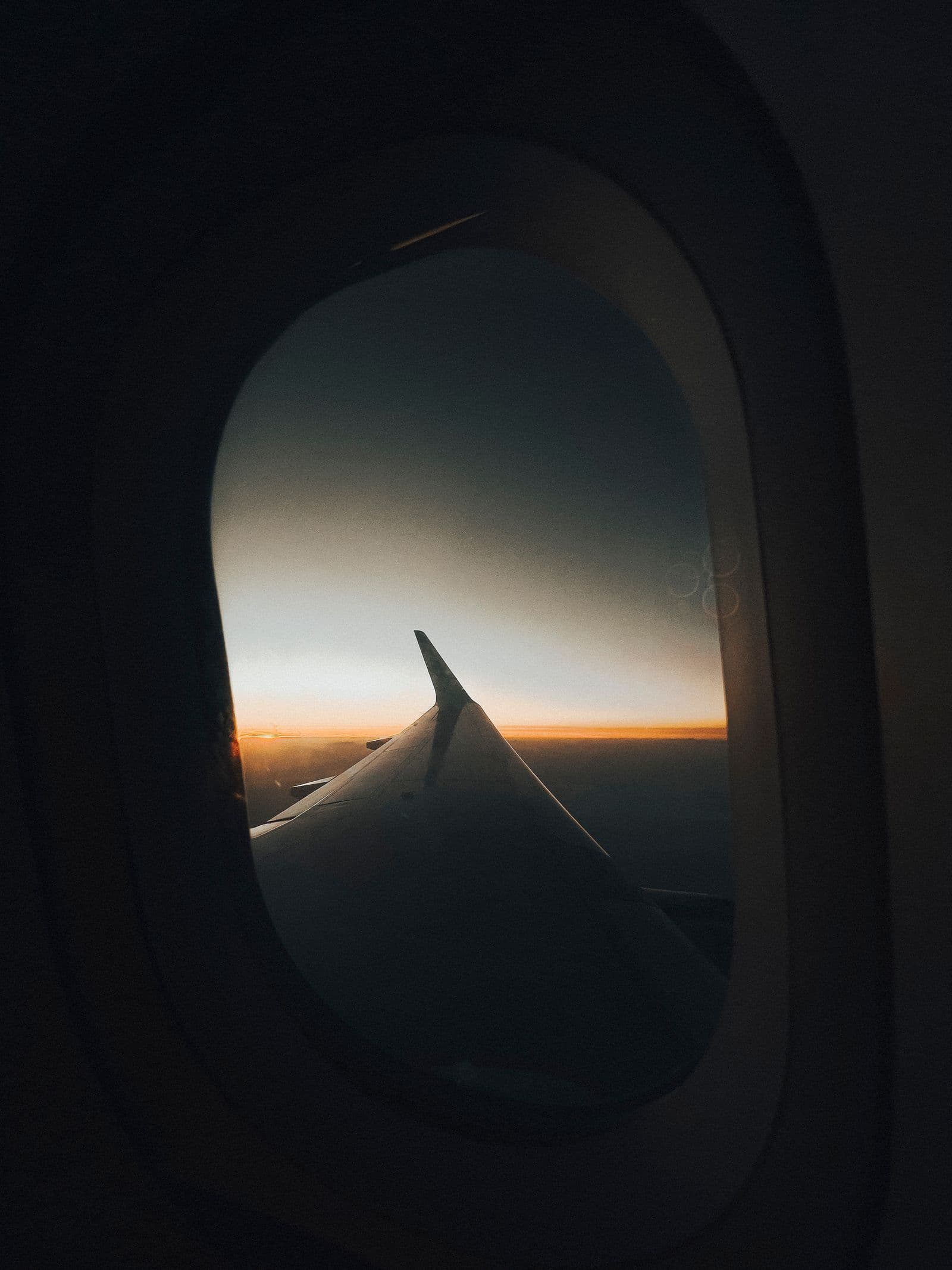 Airplane wing and a warm sunset viewed from a cabin window